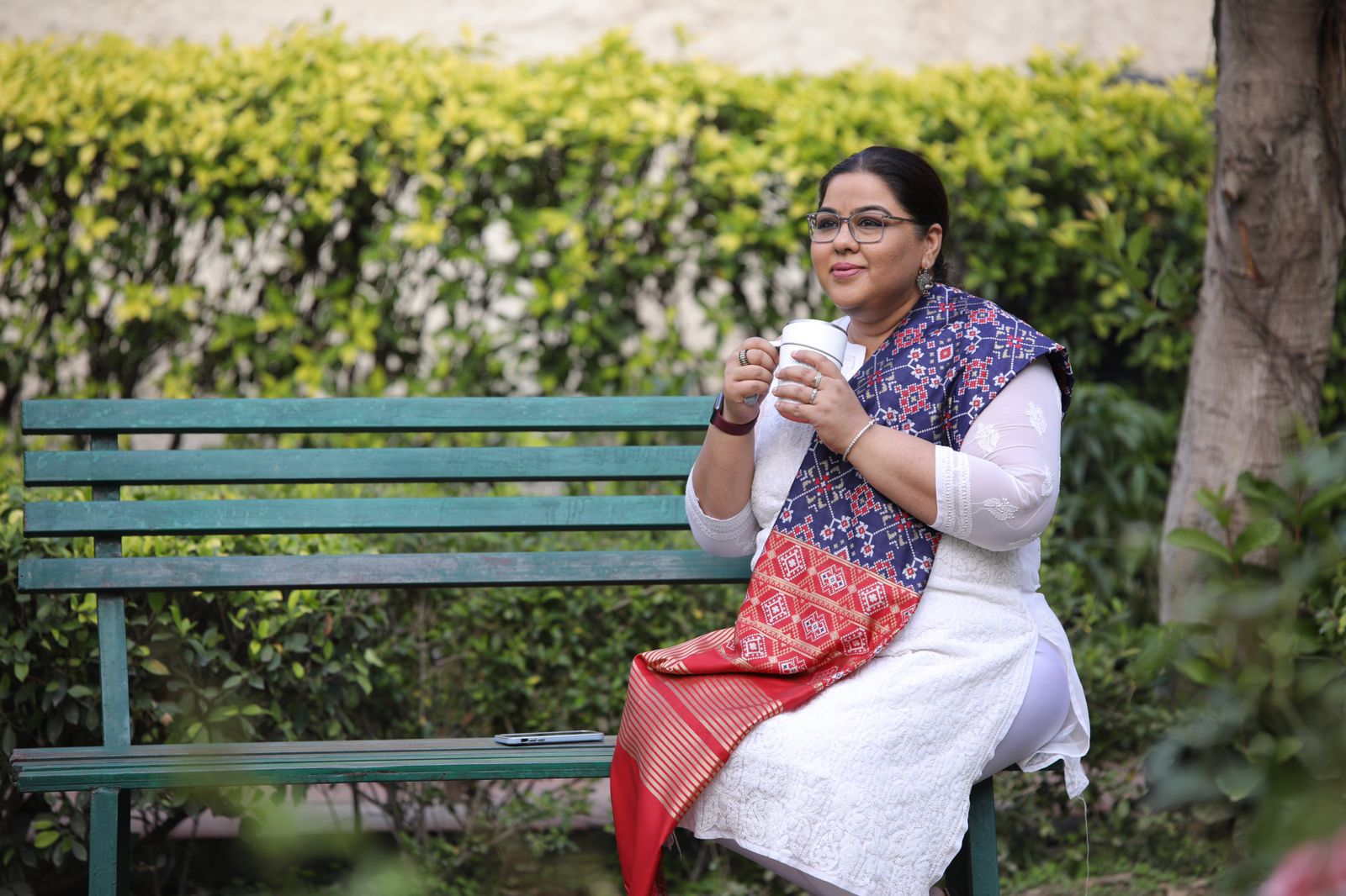 niti is sitting on the bench and having coffee